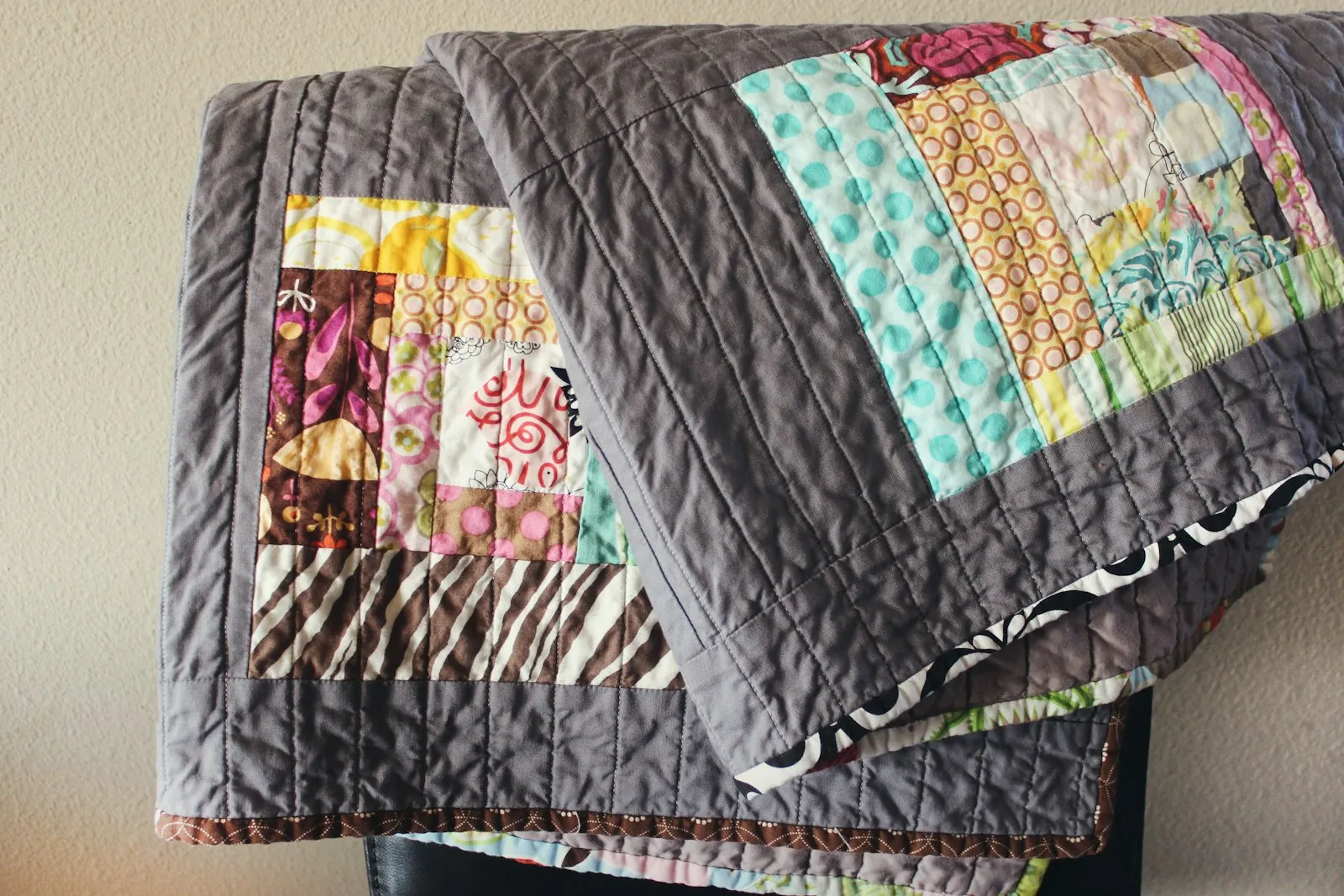 A handmade colourful quilt draped over a chair